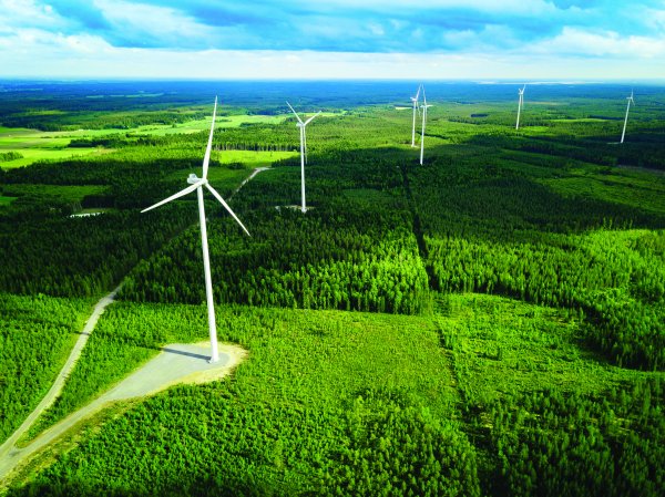 Aerial view of windmills in green summer forest in Finland. Wind turbines for electric power with clean and Renewable Energy